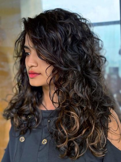 Another angle of these beautifully highlighted brunette curls, showing how the color enhances the hair's natural texture and movement.