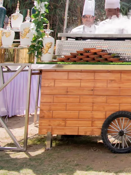 A chef preparing a dish with dramatic flair at a live station. The steam and action from the live cooking add an element of entertainment for guests at the event.