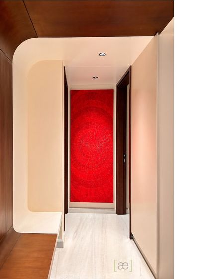 A striking red artwork creates a bold focal point in this corridor, framed by curved wooden paneling. This detail shows how we use art and architecture to create moments of visual interest in transitional spaces.