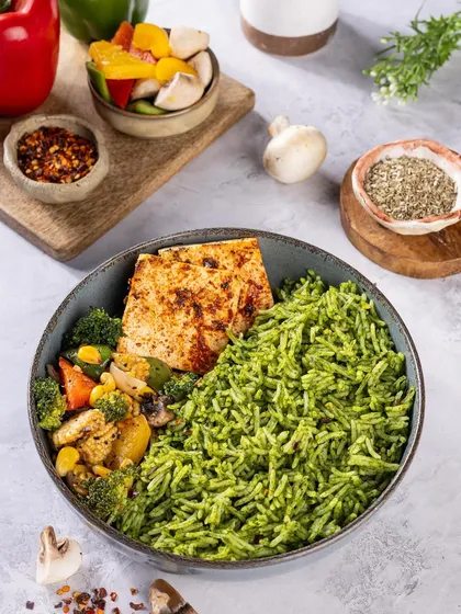 A healthy and colourful meal bowl with pesto rice, grilled paneer, and sautéed vegetables. This top-down shot clearly shows all the components, making it look both nutritious and delicious.