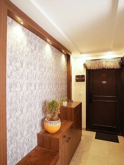 A simple yet elegant entryway with a textured accent wall, spot lighting, and a functional shoe cabinet with a seating bench.