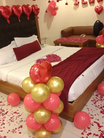 A close-up of the balloon pillar and the rose petal heart on the bed, showing the combination of different decorative elements.
