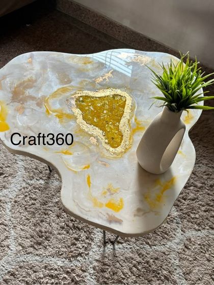 This is a finished geode coffee table with a marble effect and a yellow sapphire-like stone center, styled with a simple vase. It shows how a custom table can become a functional piece of art in your home.