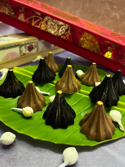 Our chocolate modaks are a modern twist on a traditional favorite for Ganesh Chaturthi. This image shows our milk and dark chocolate modaks, crafted with a smooth, rich texture and presented on a traditional banana leaf. They are a popular choice for offerings and festive gifting.