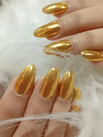 A full set of long, almond-shaped nails with a brilliant, reflective gold chrome finish.