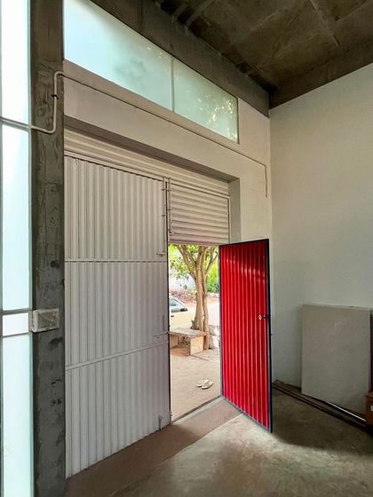 The entrance to the artist's studio features a bold red door set within a larger industrial shutter. This combination of elements creates a functional yet striking threshold between the public street and the private creative space.