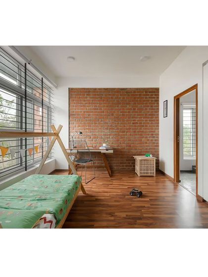The kid's bedroom features a playful tent-style bed frame and an exposed brick accent wall. Large windows ensure the room is bright and airy, creating a cheerful and inspiring space for a child to grow.
