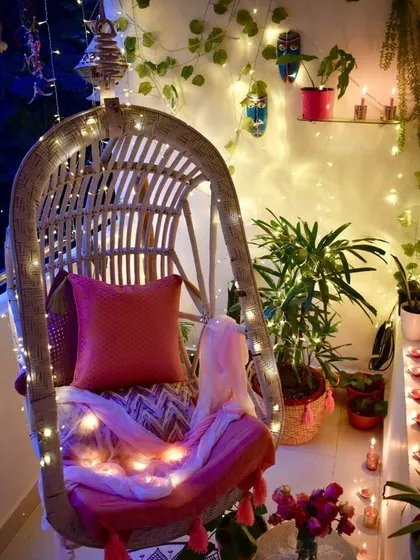 This design idea transforms a small balcony into a magical evening retreat with a comfortable swing chair, fairy lights, and climbing ivy, perfect for unwinding after a long day.