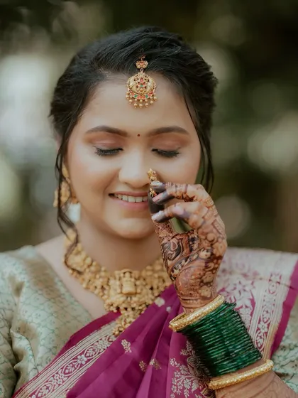 A close-up on the details. The intricate henna, the classic nath, and the soft smile of this Marathi bride highlight the beauty of her complete bridal look.