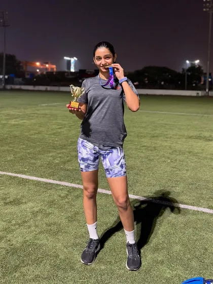 A full-length shot of Aayra with her trophy and medal on the track after her successful race. She crushed it.
