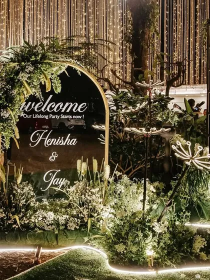 The engagement entrance at night, where the lighting transforms the space. The illuminated welcome sign, glowing floral installations, and candle wall create a magical and romantic ambiance.