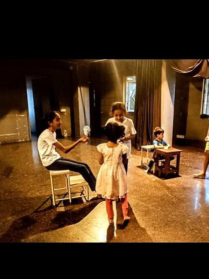 A scene being blocked during a children's theatre class. The use of simple props and lighting helps the students visualize their performance and interact with the space effectively.