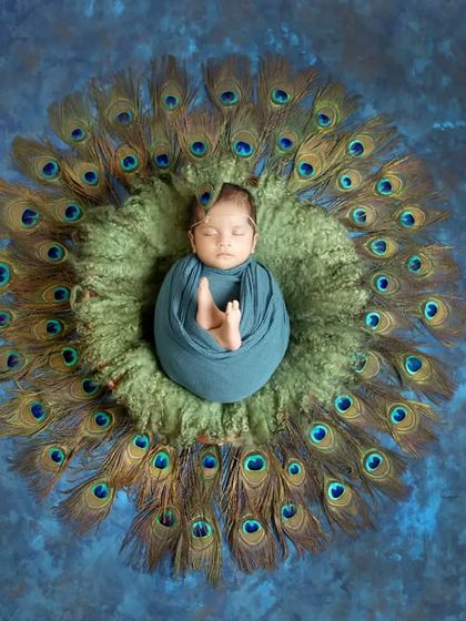 A different take on the Krishna theme, with the baby swaddled in blue against a backdrop of peacock feathers, symbolizing the beloved deity.