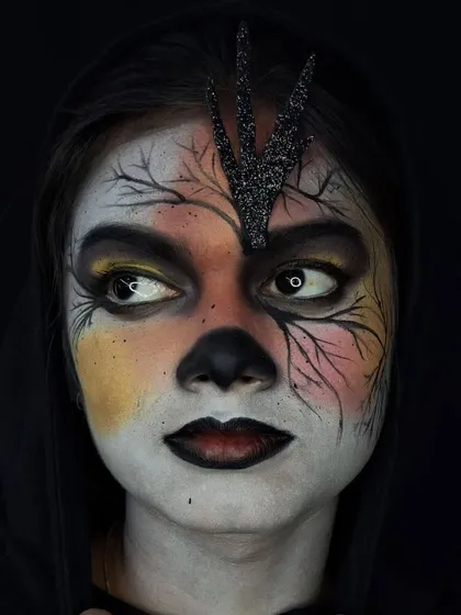 A side-glancing pose to show how the makeup looks from different angles. The white contact lenses create a striking, non-human effect that is visible even from the side.