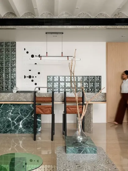 The breakfast counter, with its bold green marble base and textured veneer top, is a perfect example of how we use materials to create visually pleasing and functional spaces.