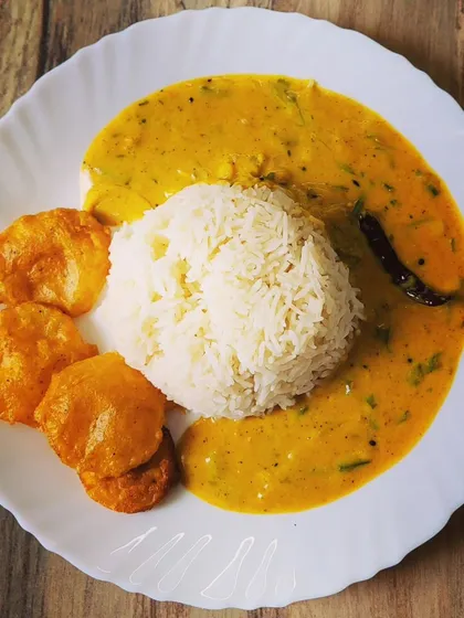 My go-to comfort food, Punjabi Kadhi Chawal. This is a beautifully plated meal of steamed rice surrounded by a tangy yogurt and gram flour curry, served with crispy homemade aloo pakoras on the side.