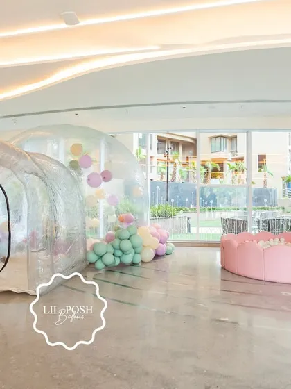 A wide shot of the play area at "Aahana's Onderland," featuring a clear bubble house filled with balloons and a soft pink ball pit with a slide.
