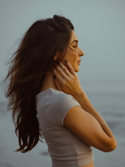 A quiet, profile portrait against the sea. The soft, fading light creates a peaceful and introspective mood.