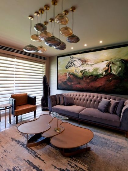 A detail of the living room, focusing on the tufted lavender sofa and a unique cluster of pendant lights. The organic shapes and soft colors contribute to the room's serene and artistic atmosphere.