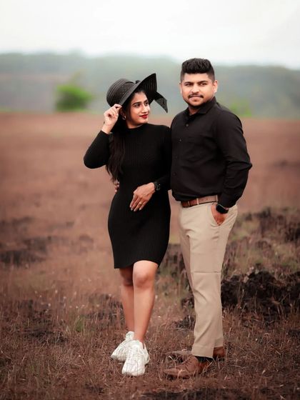 A stylish pre-wedding portrait of a couple in a field, their coordinated black outfits creating a chic look.