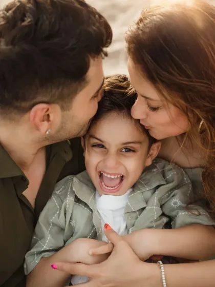 A joyful close-up of a family sharing kisses and laughter at the beach. These candid moments are what make family lifestyle photoshoots so memorable and full of emotion.