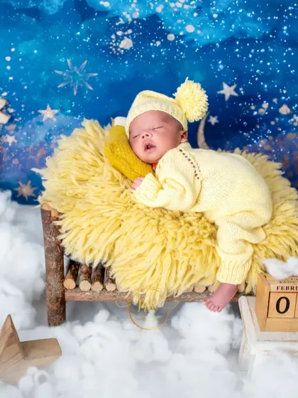 A full view of the starry night setup, with a sleeping newborn on a miniature wooden bed, complete with a date block showing "February 06".