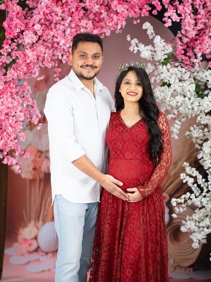 A sweet couple's portrait against a wall of cherry blossoms. The simple outfits and loving pose create a romantic and timeless image.