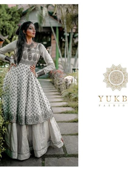 The model posing in a garden setting, demonstrating the graceful silhouette of the layered Anarkali gown.