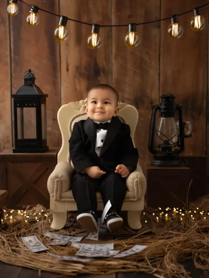 The real "Boss Baby" in a tiny tuxedo, sitting in a miniature armchair. This themed toddler photography session is full of personality and charm.