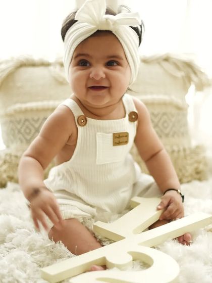 Celebrating the half-birthday milestone. This six-month-old is sitting up proudly with her "1/2" sign in a bright, clean, and modern setup.