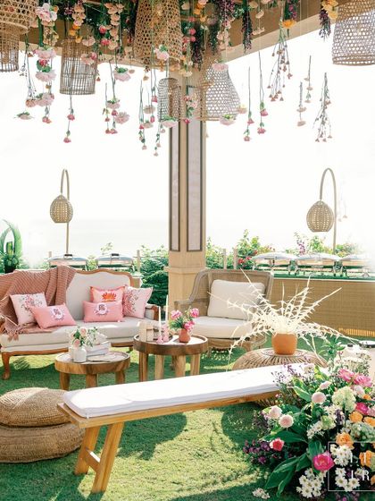 A lounge area at 'Villa Brissa' with rattan furniture and a ceiling installation of hanging baskets and flowers. The design created a symphony of textures, colors, and layers.