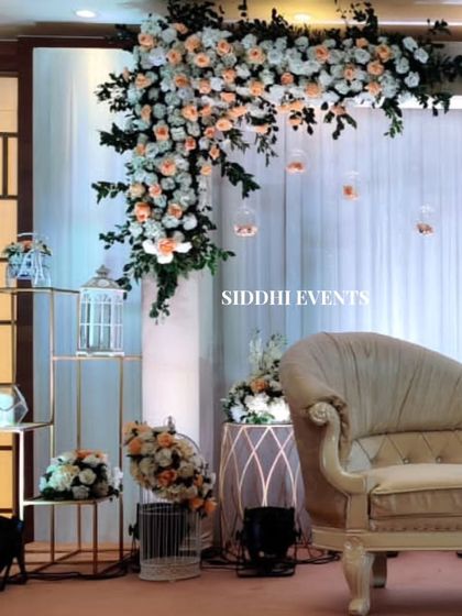 A close-up view of the elegant reception decor, showing the cream chaise lounge, peach and white floral arrangements, and decorative birdcages on tiered stands.