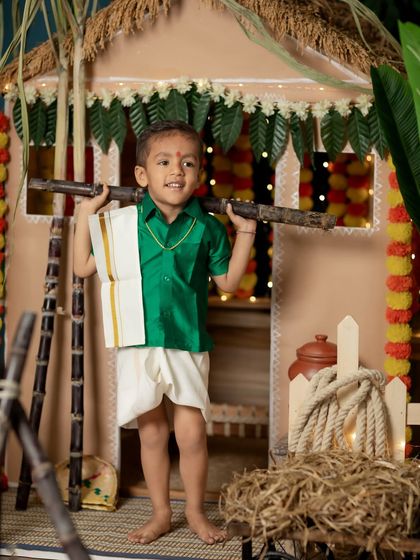 A little boy in a traditional veshti and shirt, ready to celebrate Pongal.