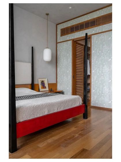 A view of the custom four-poster bed, showing how it commands the space with its bold red and black frame.
