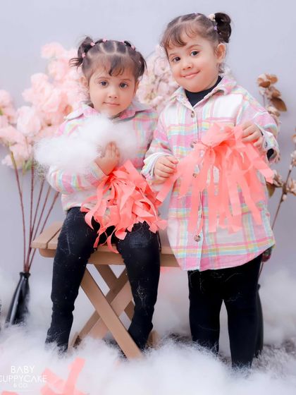Twin girls in a beautiful floral and cloud-themed setup. We love creating coordinated shoots for siblings.
