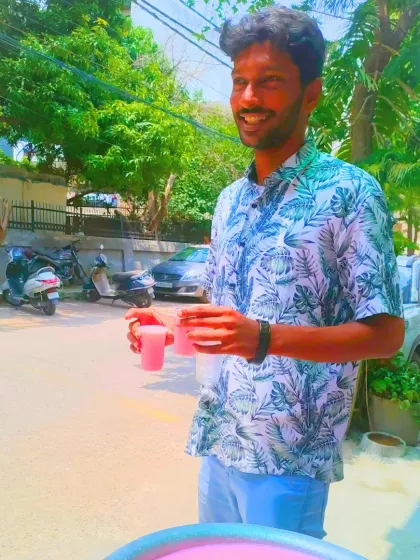 A volunteer smiles as he holds out glasses of sharbat. The joy of giving is a core part of our *Sachi Sewa* philosophy.