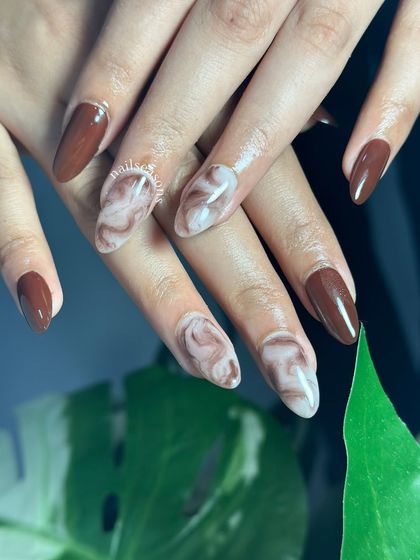 Chocolate marble magic. This delicious-looking set features a rich brown polish with creamy marble accent nails.