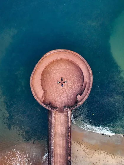 A perfect top-down shot of the circular bastion of Sinquerim Fort, with a person standing in the middle, giving a sense of scale.