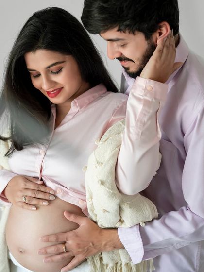 A sweet and gentle moment between an expecting couple. The soft fabrics and light colors add to the tender atmosphere.