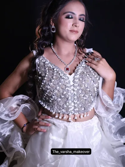 A close-up of the white cocktail outfit, focusing on the heavily beaded blouse and the dramatic makeup look.