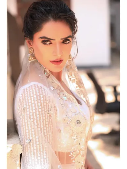 A powerful portrait with a direct, intense gaze. This shot combines the softness of the traditional white outfit with a strong, confident presence.
