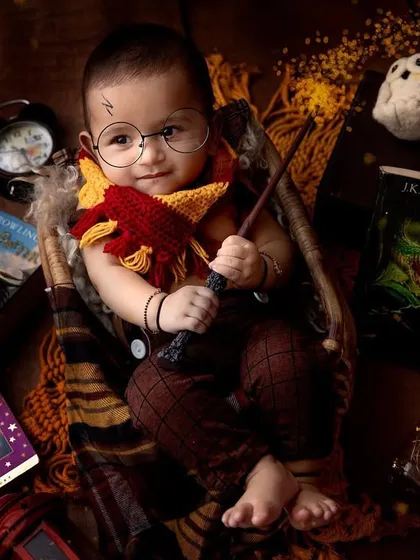 Wingardium Leviosa! This Harry Potter theme is a favorite for so many parents, and look at this little wizard. With the Gryffindor scarf, round glasses, and magic wand, this studio portrait brings a little bit of Hogwarts magic to life.