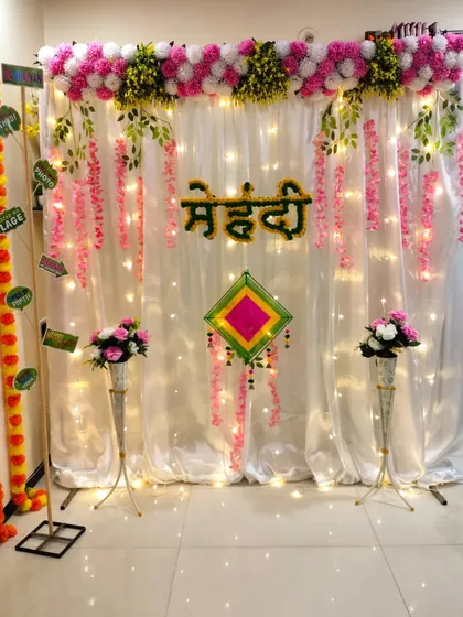 Another angle of the simple home Mehndi setup, showing the "Mehndi" sign made of flowers and the elegant floor vases. It's a clean and pretty look that doesn't overwhelm the space.