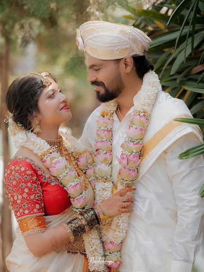 The couple shares a loving look, their garlands connecting them. This portrait highlights their bond and the beauty of their wedding attire.