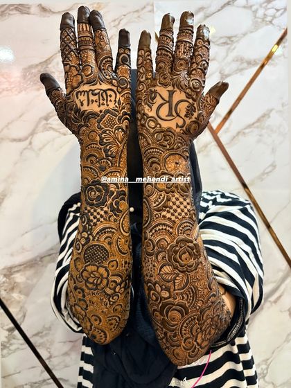 This design features the groom's initial 'R' on one palm and the name 'Sultana' in Arabic on the other.