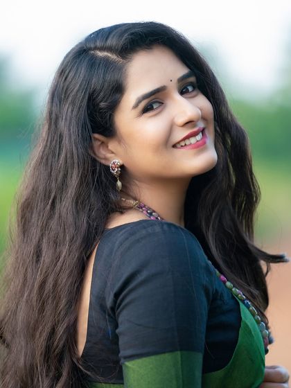 A simple and elegant portrait of a model in a green saree. The focus is on her natural beauty and calm expression.