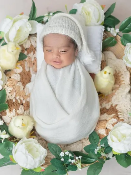 A wreath of white flowers and greenery creates a beautiful frame for this sleeping baby.
