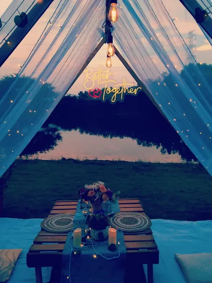 The view from inside the tent at dusk, showing the magical ambiance created by the fairy lights and the serene natural surroundings.