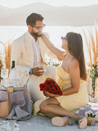 A romantic moment captured. The custom white suit provides a sharp, elegant look for this special seaside proposal, proving that great tailoring is right for every big moment.