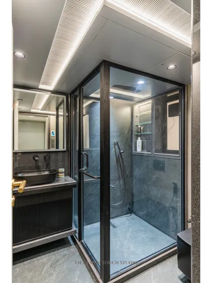 A full view of the bathroom, showing the cohesive use of dark tiles and modern fixtures. The linear lighting in the ceiling adds to the sleek, contemporary feel.
